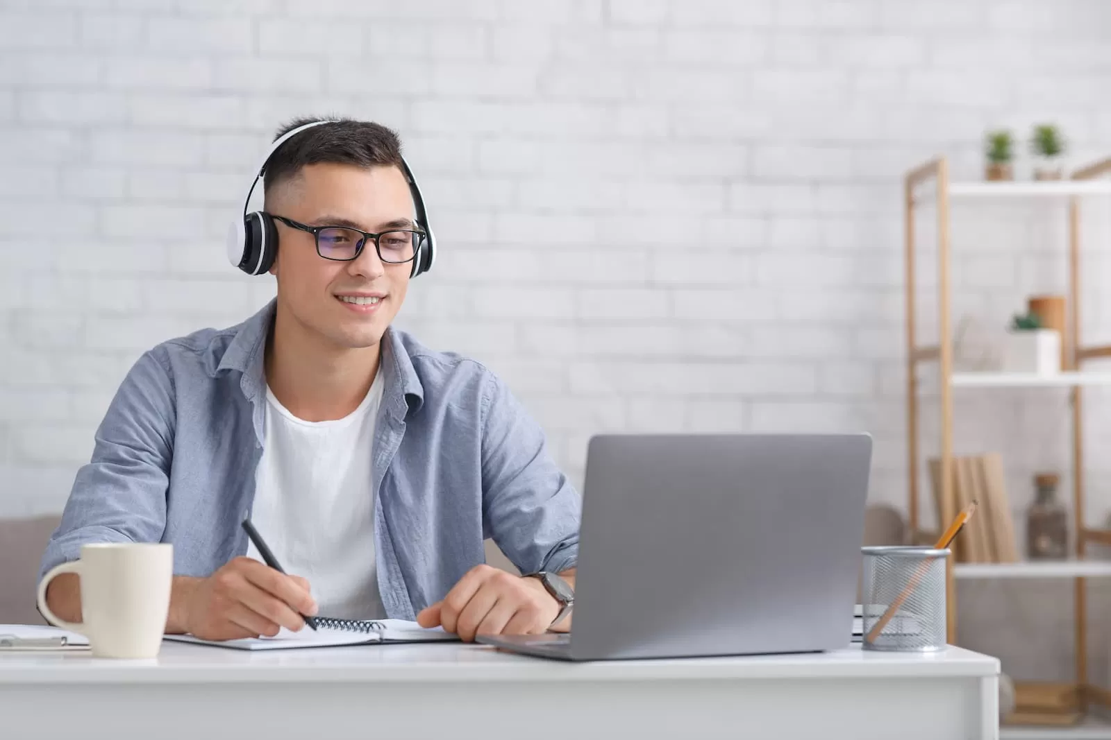 alumno joven con gafas y cascos frente a un portatil en clases de ingles online
