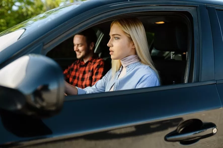 chica adolescente rubia conduce por primera vez con profesor autoescuela