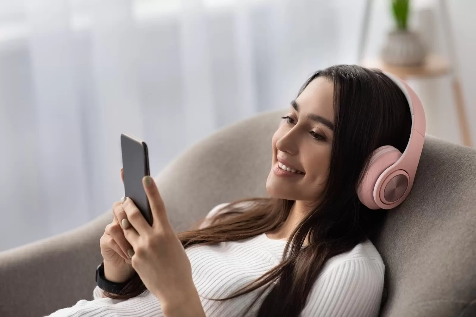 chica joven en el sofa con cascos aprende ingles desde el movil