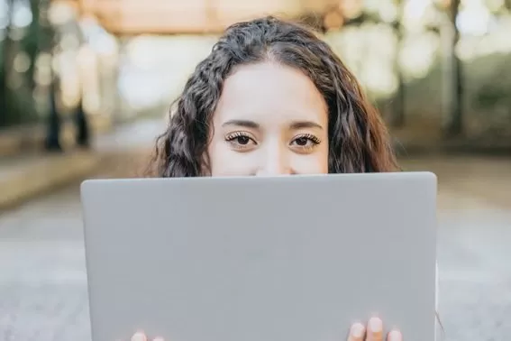 chica morena mira a traves de un portatil estudia online