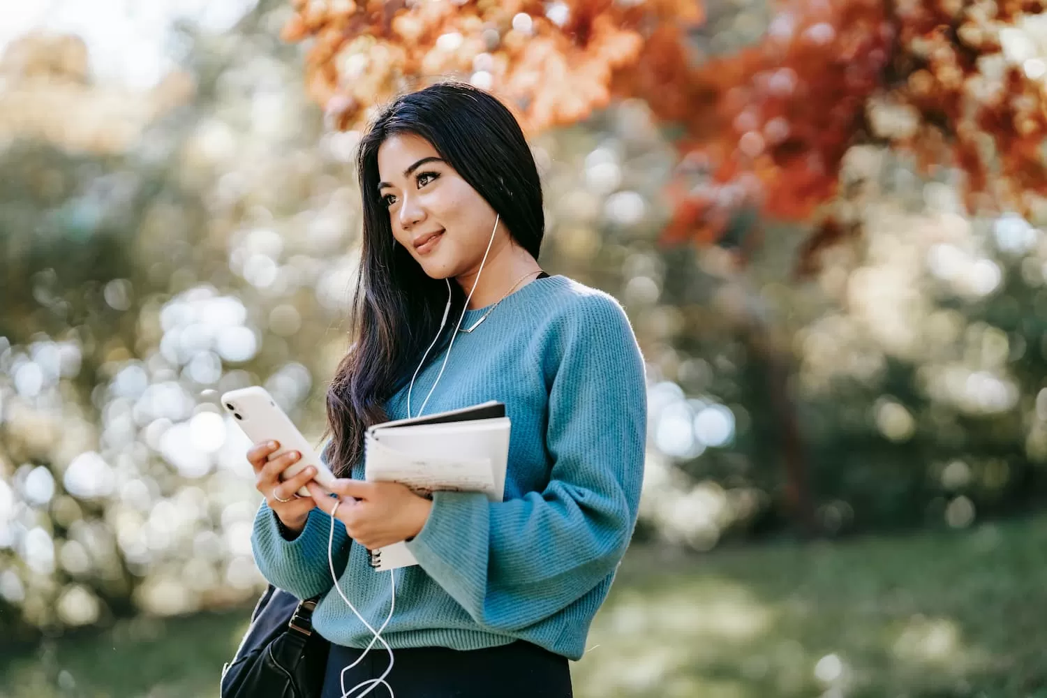 chica morena pelo liso de pie en el parque con el movil en epoca de examenes