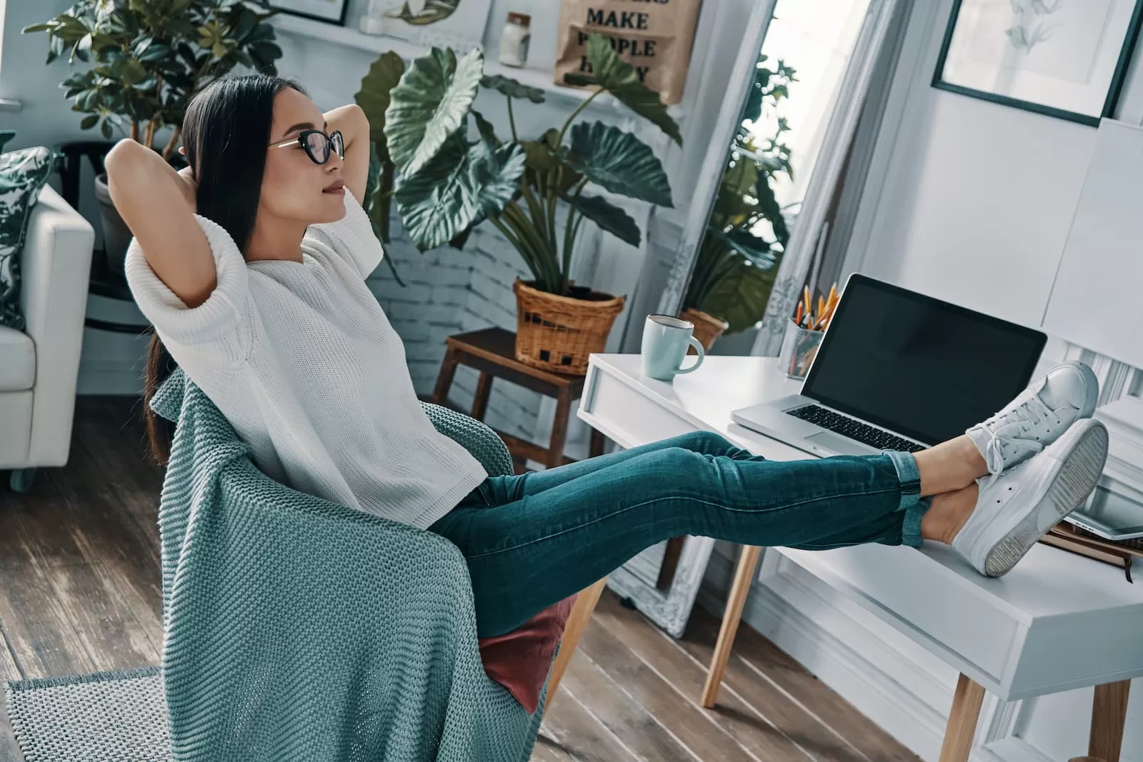 chica relajada con los pies sobre la mesa porque no tiene que hacer su TFG