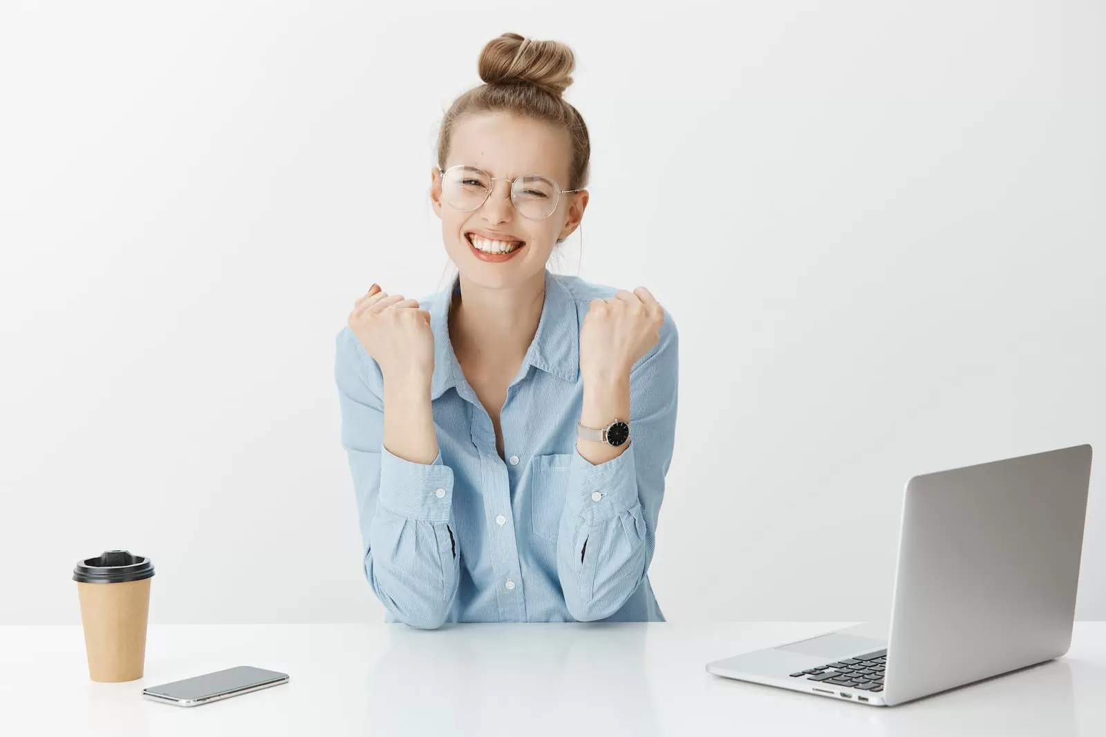 chica rubia con camisa azul apoya codos en mesa sonriente celebra tfg