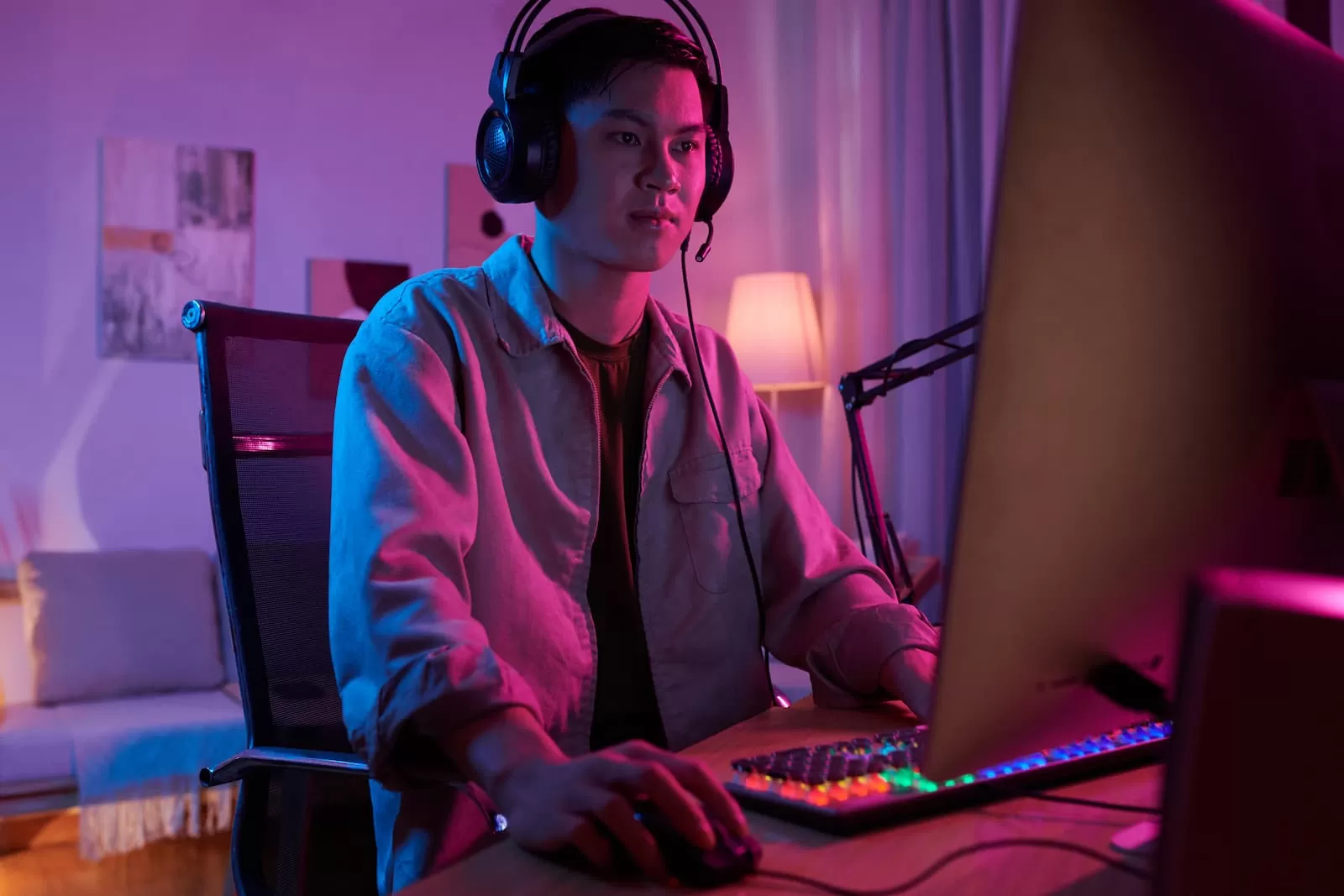 chico coreano sentado juega a videojuegos en el ordenador