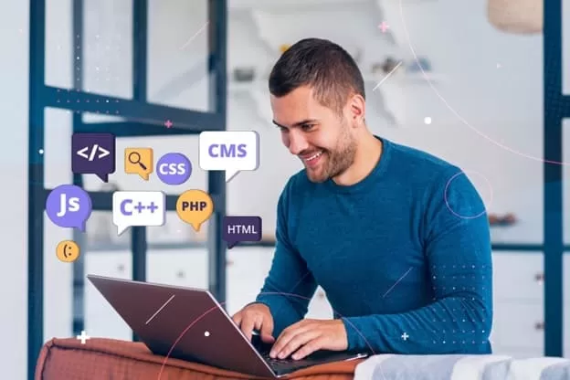 chico joven sonrie mientras programa en su portatil