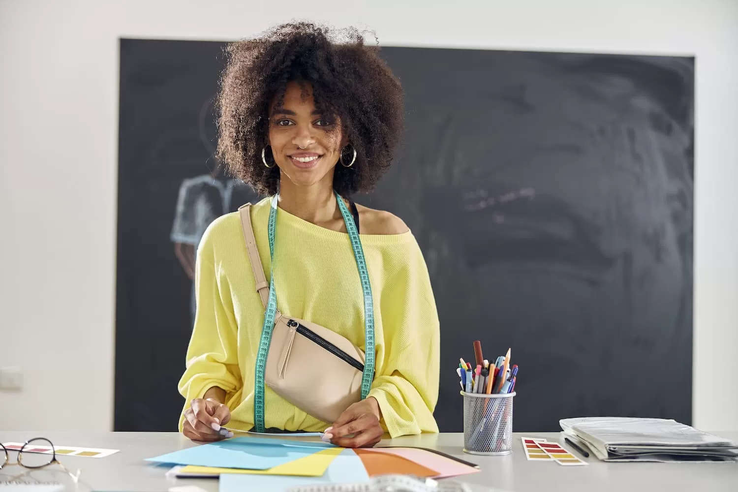 estudiante afroamericano sonriente con hojas de papel de colores en la mesa