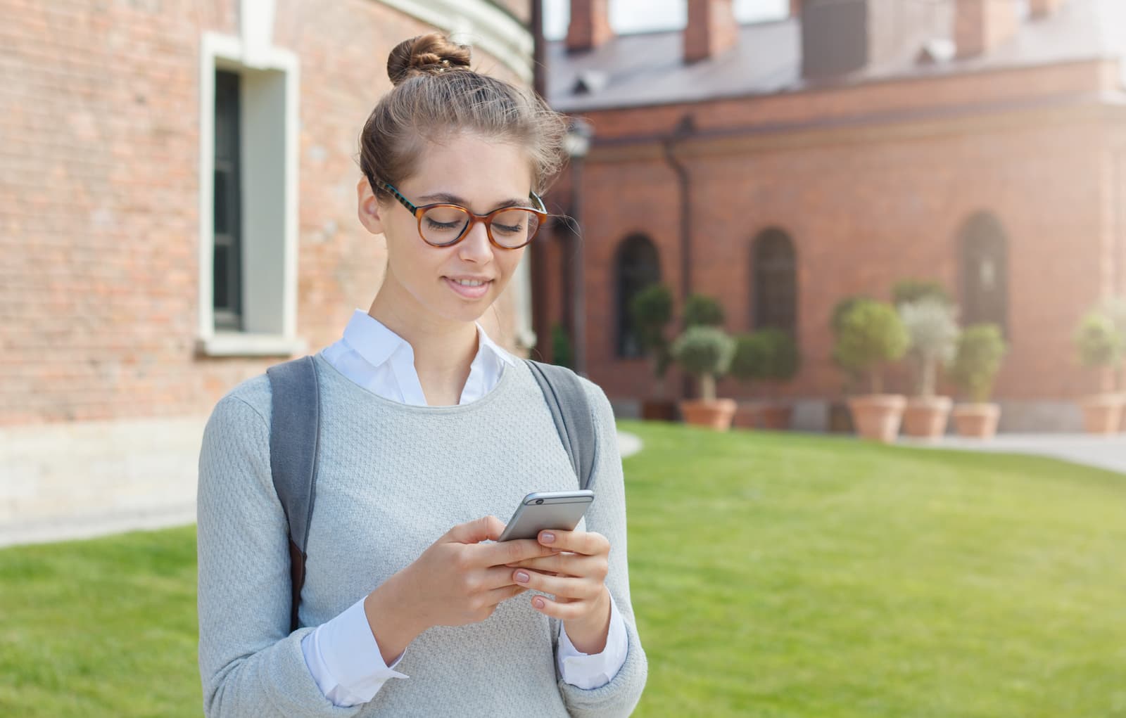 estudiante joven universitaria europea sosteniendo el telefono movil en sus manos