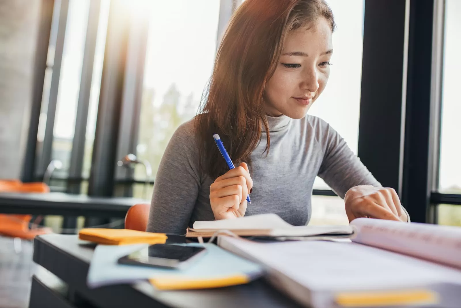 estudiante universitario feliz prepara tfg sentada en una mesa