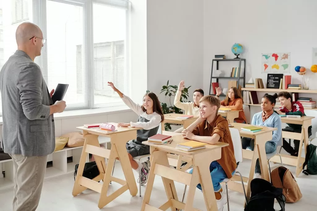 estudiantes levantan la mano para responder a pregunta en clase de academia