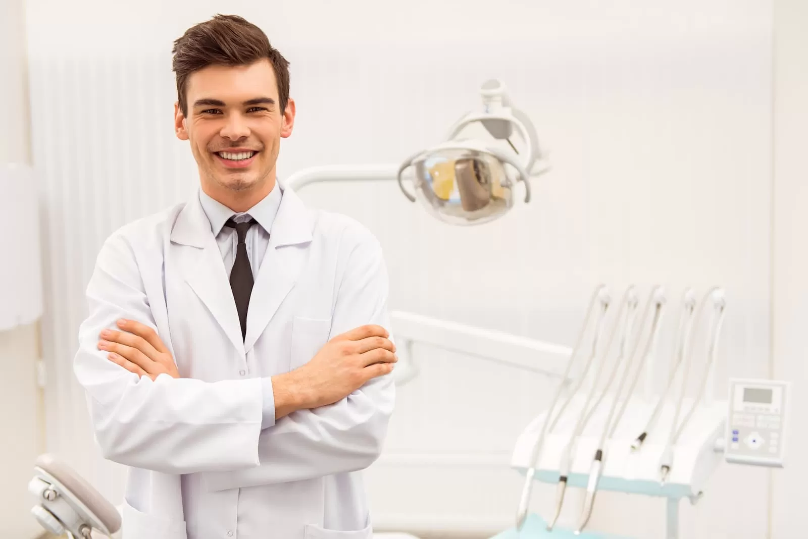 joven detista sonrie en la clinica de brazos cruzados