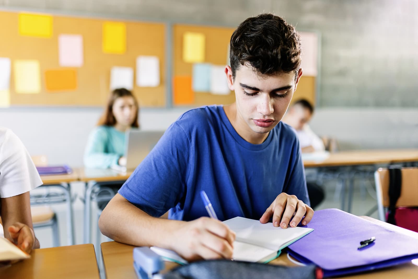 joven estudiante de secundaria escribiendo a un cuaderno en clase