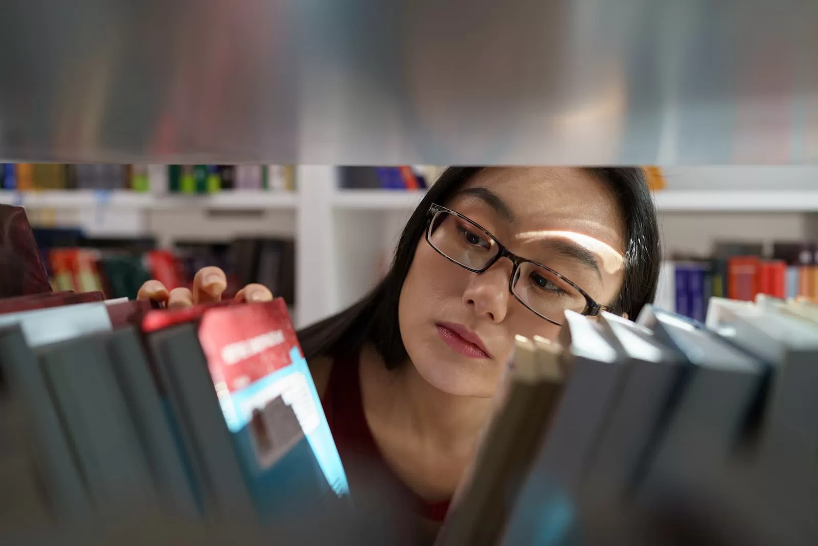 joven universitaria asiatica en busca de libros y fuentes en la biblioteca