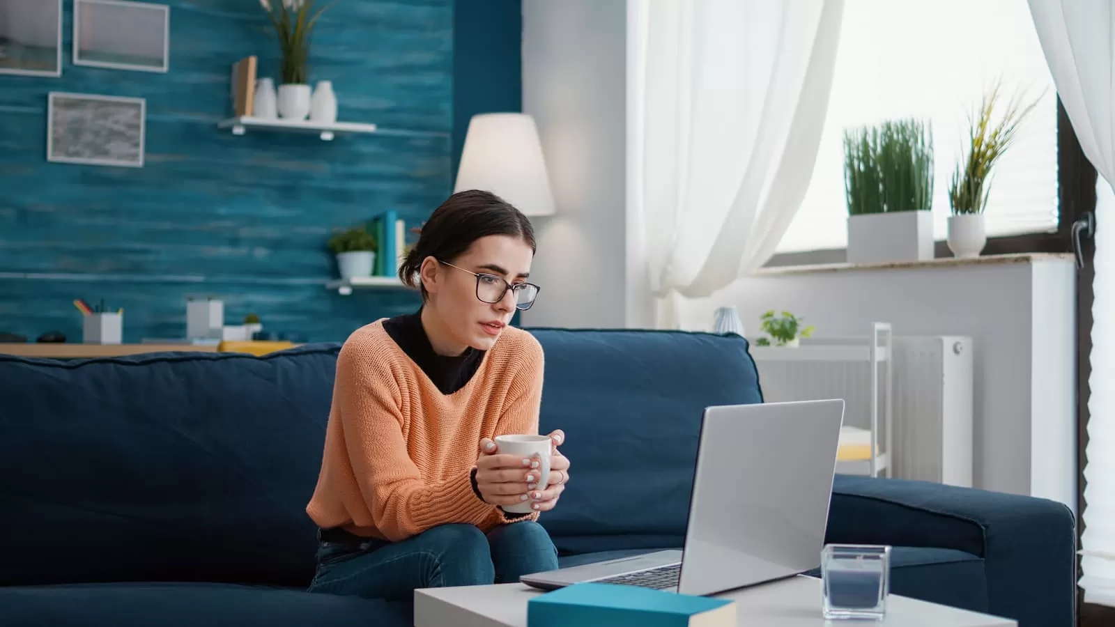 mujer estudia con un café en la mano con su portatil