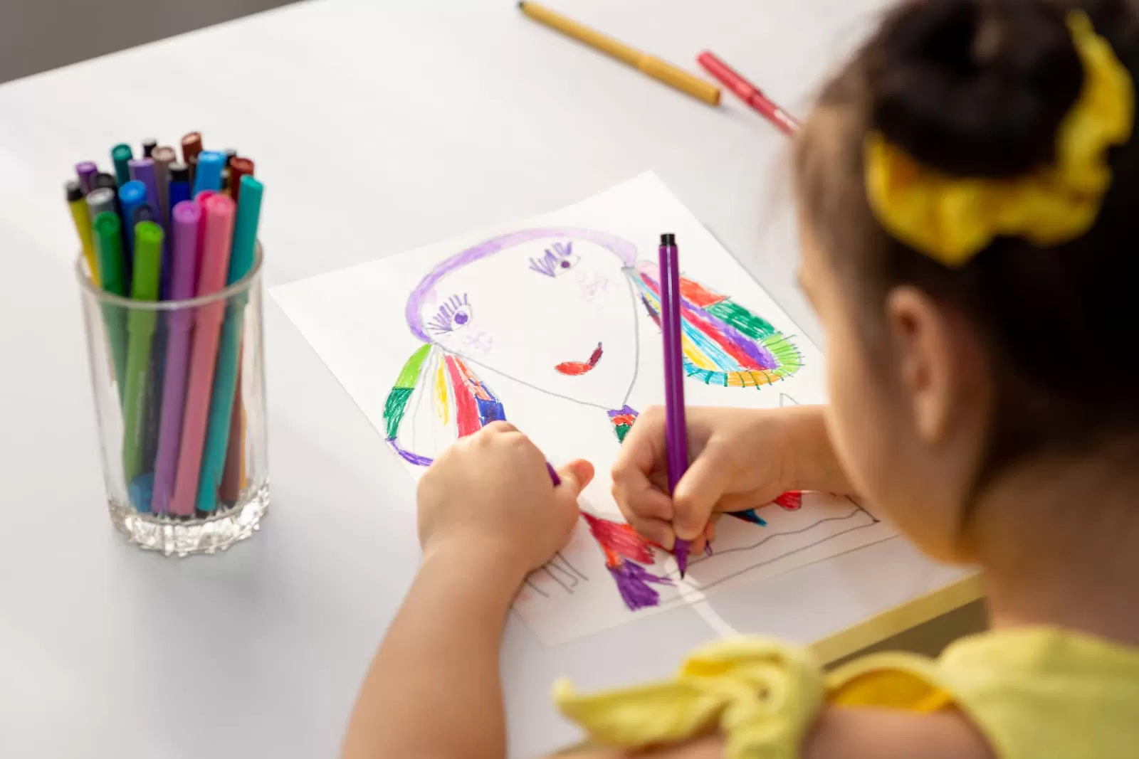 niña morena dibujando con rotuladores de colores