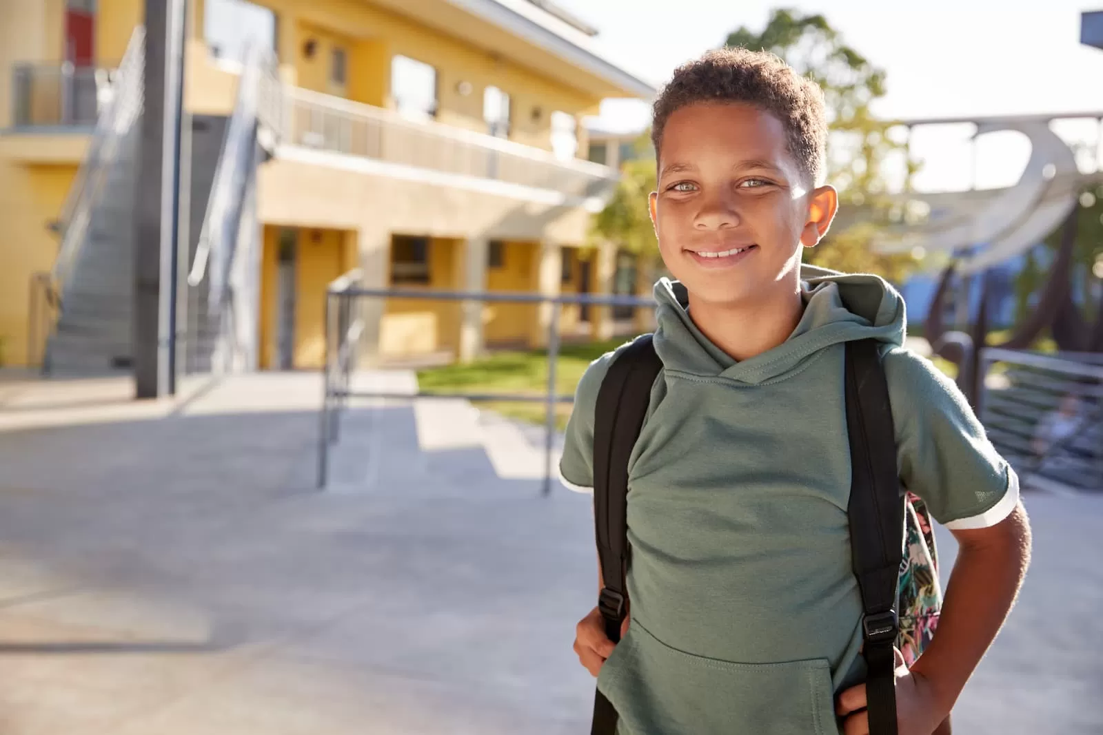niño negro ojos azules con mochila camino hacia la escuela
