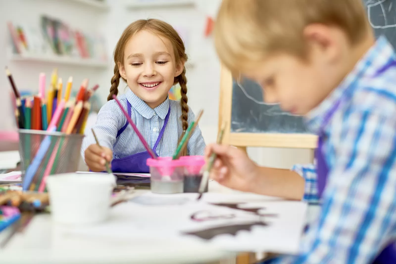 niños felices utilizan pintura en clase de arte