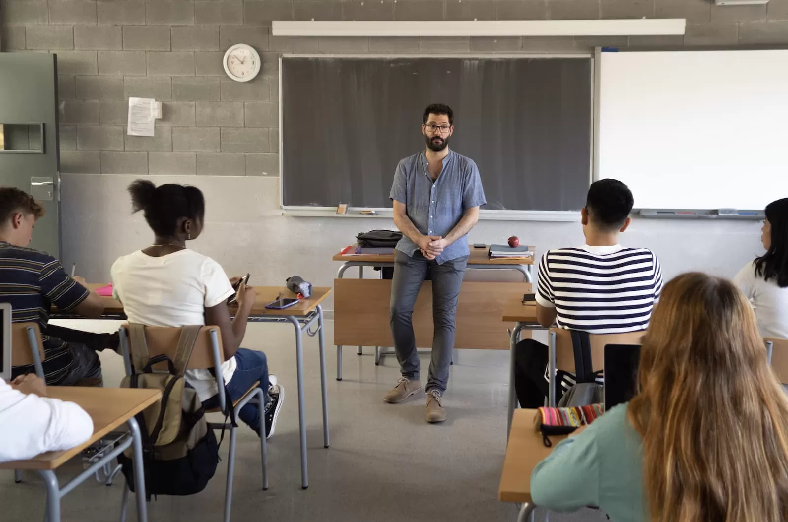 profesor de pie frente a su esa explicando la lección de castellano en el aula