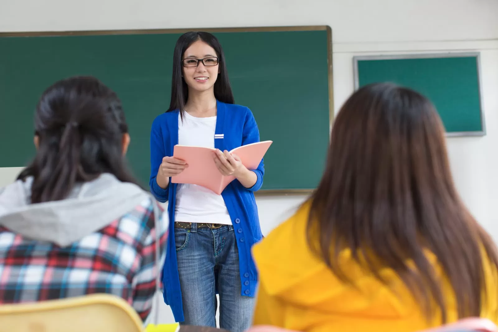 profesor universitario con cuaderno y estudiantes en el aula