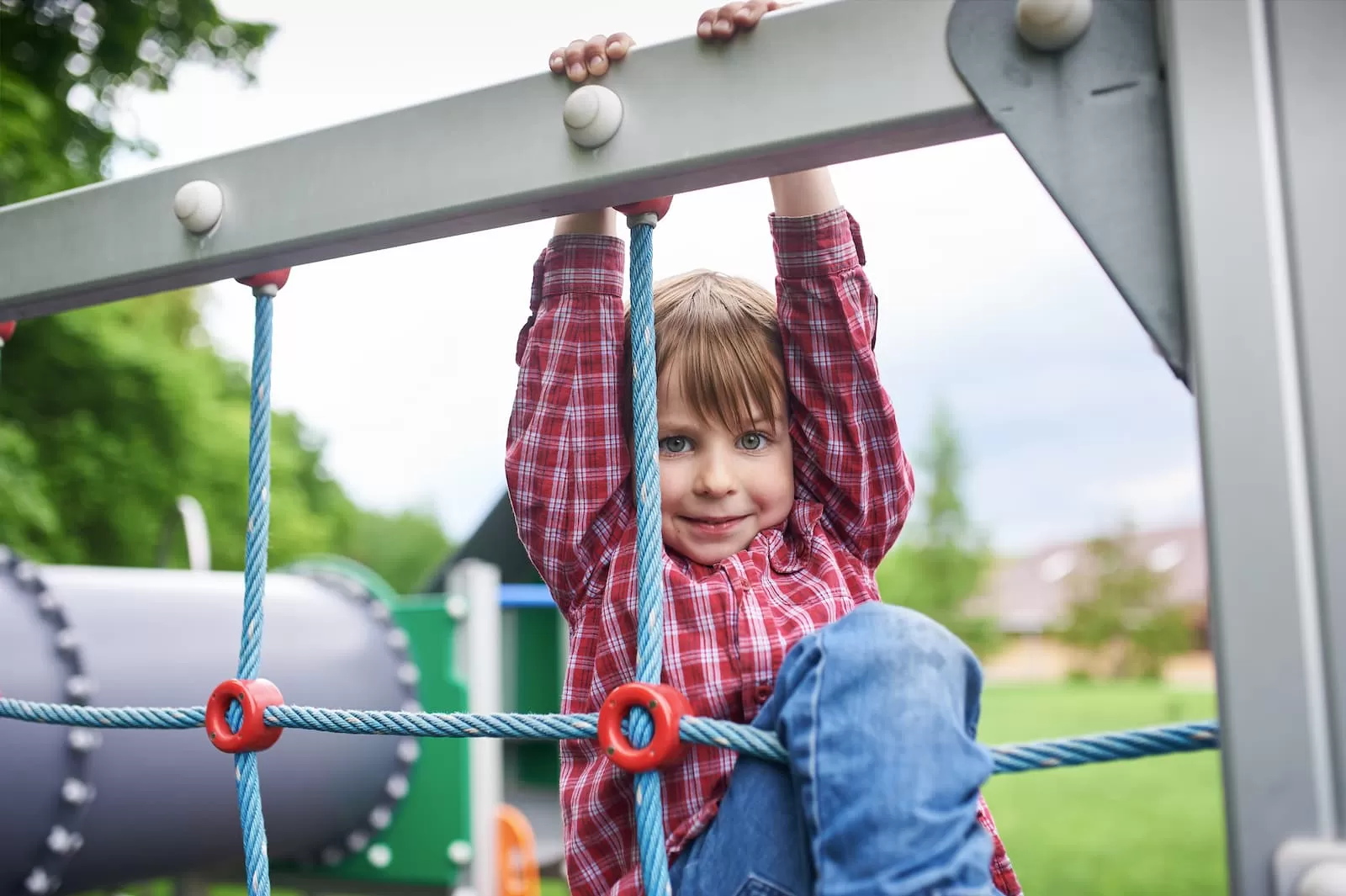 retrato al aire libre de un niño en edad preescolar en el patio de recreo sobre fondo verde natural mientras juega