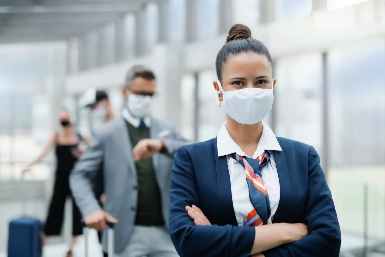 retrato de azafata de pie en el aeropuerto usando mascarilla