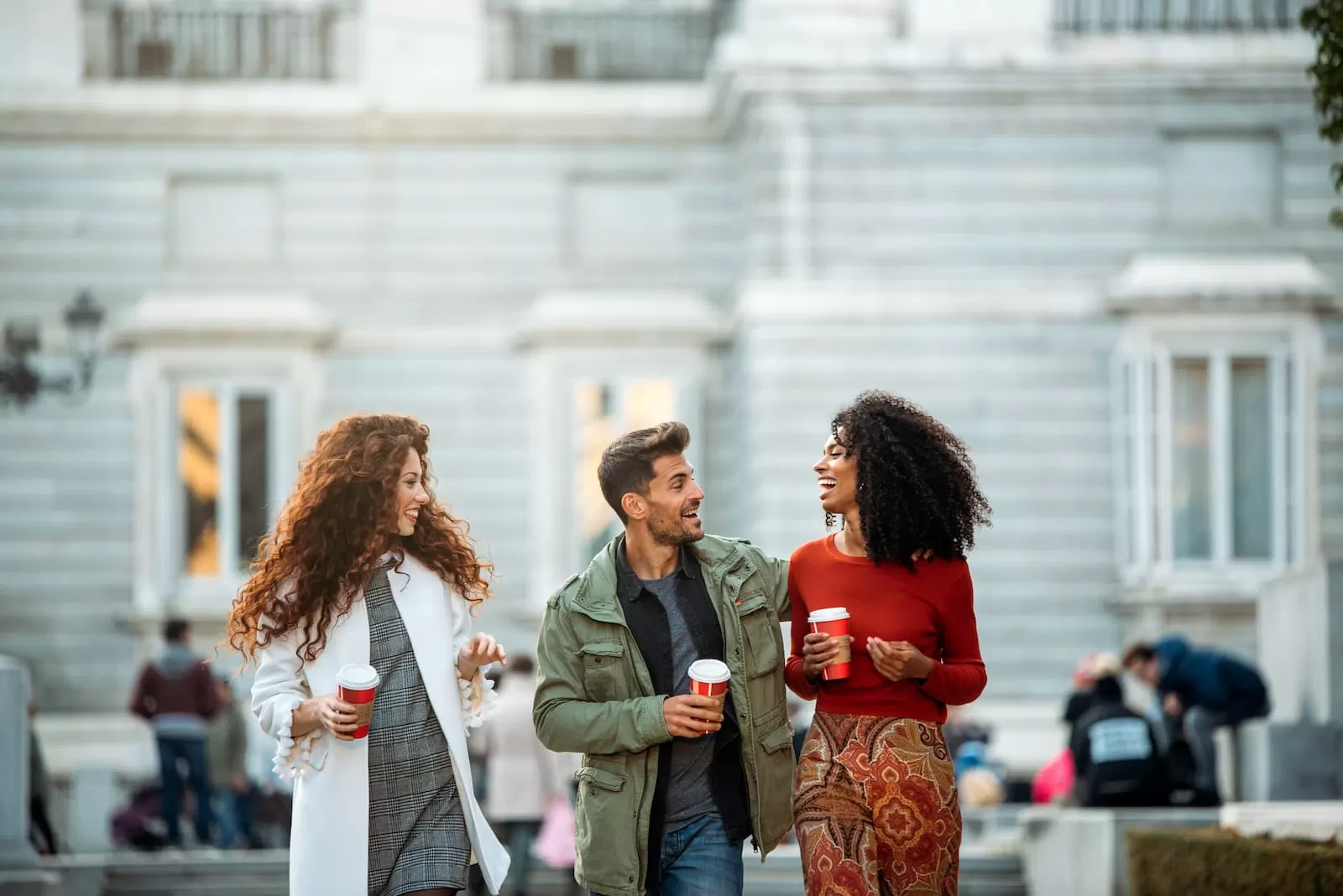 tres jovenes amigos paseando y tomando cafe