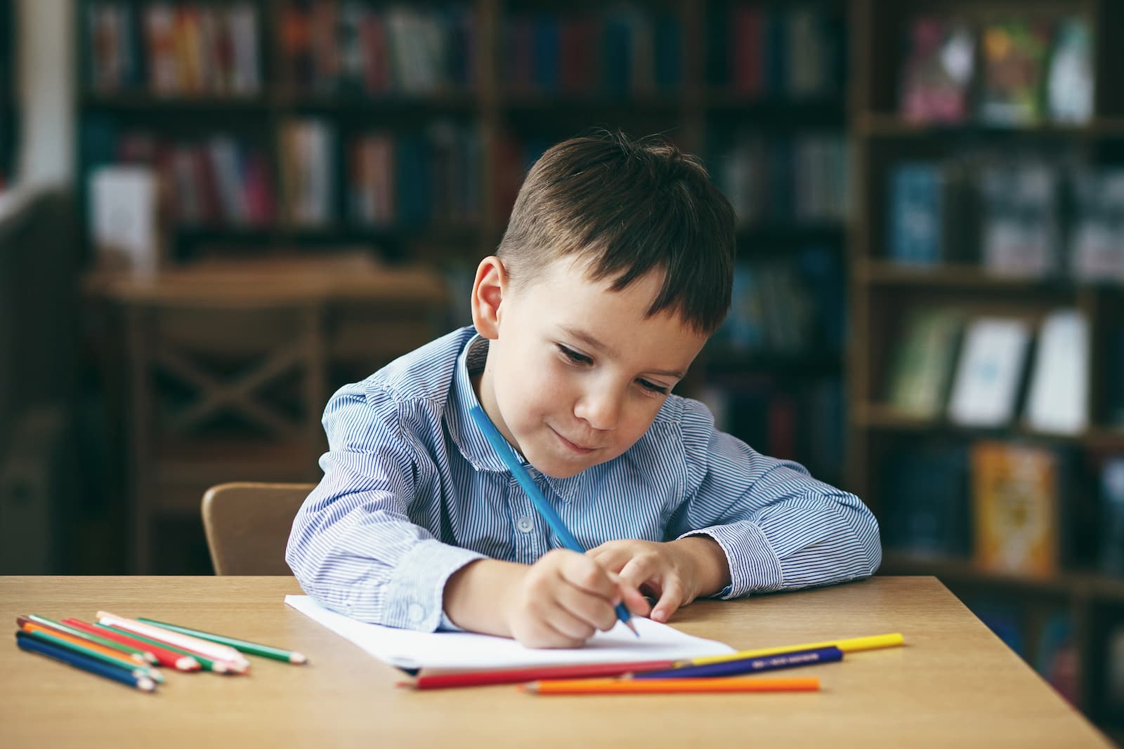 un niño de preescolar dibujando sentado sobre una mesa