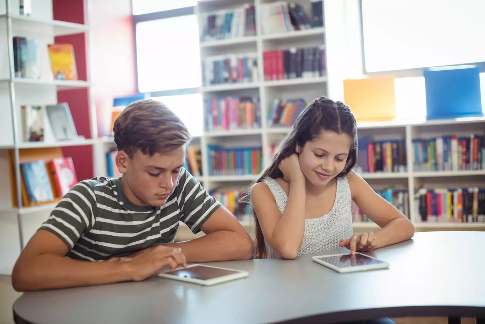 dos jovenes estudiantes mirando una tablet en la biblioteca