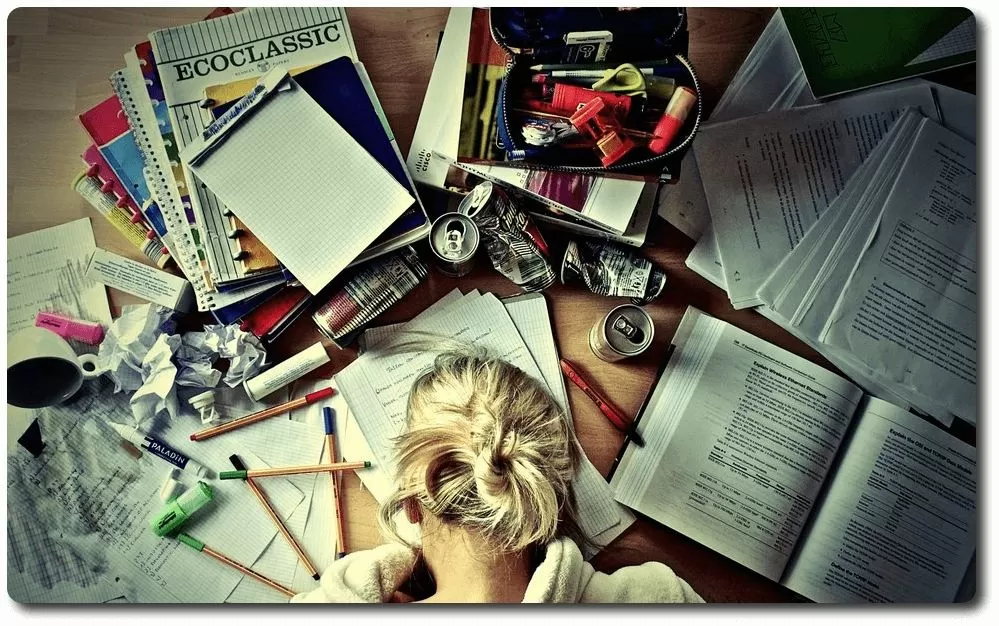 Chica apoya la cabeza en la mesa sobre documentos y libros